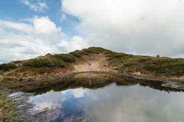Woman on hilly bank of pond landscape photo. Beautiful nature scenery photography with sky on background. Idyllic scene. High quality picture for wallpaper, travel blog, magazine, article