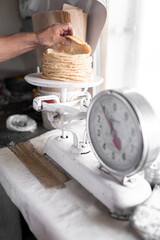 Fototapeta na wymiar An adult tortilla maker is weighing a stack of tortillas using an analog scale