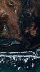 aerial view of iceland coastline in vertical black sand and brown vegetation and rivers flowing...