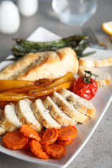 Tasty cooked chicken fillet and vegetables served on grey table. Healthy meals from air fryer