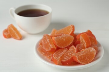 Tasty orange jelly candies on white table