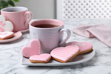 Delicious heart shaped cookies and cup of tea on white marble table