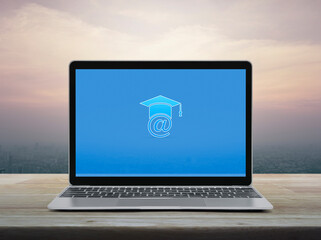 E-learning flat icon on modern laptop computer monitor screen on wooden table over office city tower and skyscraper at sunset sky, vintage style, Business study online concept