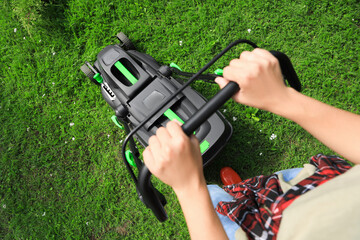 Above view of woman cutting grass with lawn mower in garden, closeup