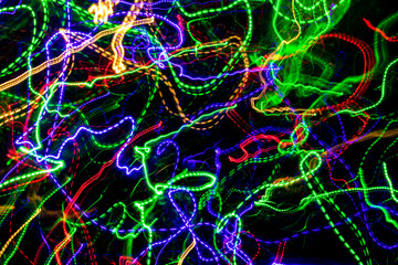 The chaotic blurred lines of color lights on dark background. Colorful lights blurred by motion.