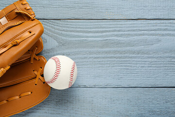 Leather baseball glove with ball on grey wooden table, top view. Space for text