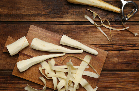 Peeled fresh parsnips and strips on wooden table, flat lay
