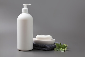 Obraz na płótnie Canvas Soap bar, bottle dispenser and towel on grey background, space for text