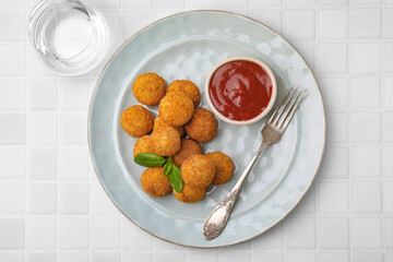 Delicious fried tofu balls with basil and sauce on white tiled table, top view
