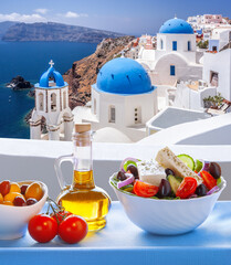 Greek food against famous churches in Oia village on Santorini island in Greece - 560357760