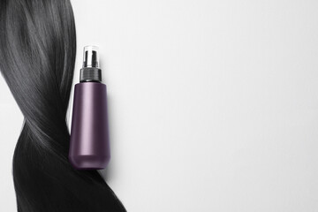 Spray bottle with thermal protection and lock of brunette hair on light background, flat lay. Space for text