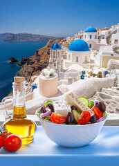 Greek food against famous churches in Oia village on Santorini island in Greece - 560357982