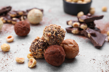 Tasty chocolate candies and nuts on light grey table