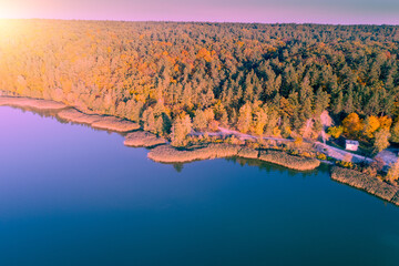 Lake in the autumn in the early morning. View of lakeshore with colorful trees. Aerial view