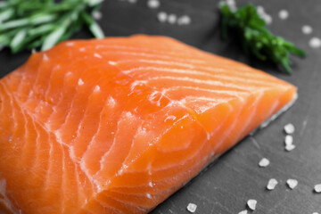 Fresh raw salmon and ingredients for marinade on black table, closeup