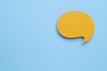 Paper speech bubble on light blue background, top view. Space for text