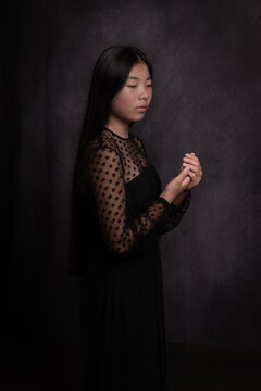 fine art studio portrait of a young asian woman in classic glamour black dress 