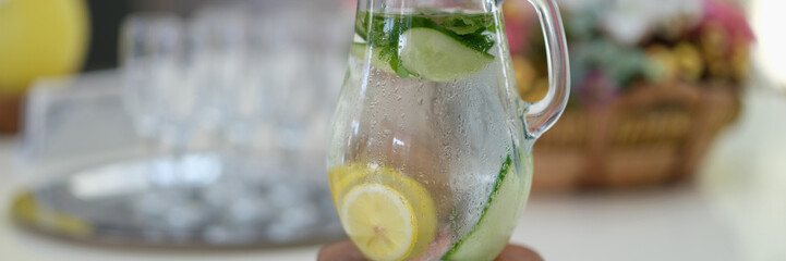 Jug of cold cucumber lemonade on table
