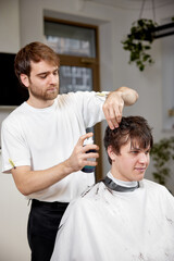 young caucasian man getting haircut by professional male hairstylist