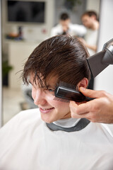 Professional hairdresser during work with man client with hair dryer in barber shop. Haircut in the barbershop.