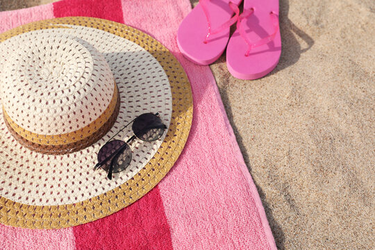 Beach towel with slippers, straw hat and sunglasses on sand
