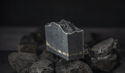 Piece of natural charcoal soap on real coals on a dark background. Concept of making and using organic eco soap and cosmetics