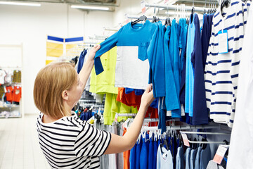 Woman chooses children clothes in store