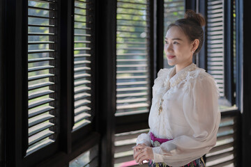 Tourist an Asian Thai woman dressed in traditional Thai dress at the old house in Lampang, Thailand. Retro fashion style concept.