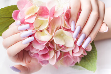 Girl's hands with a soft purple manicure.