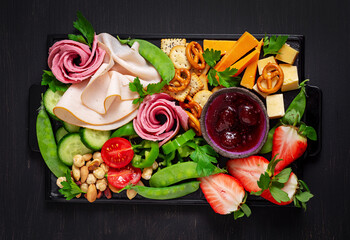 Antipasto platter cold sliced ham, salami, crackers, strawberries, vegetables and cheese platter on...