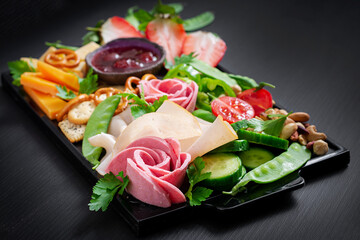 Antipasto platter cold sliced ham, salami, crackers, strawberries, vegetables and cheese platter on...