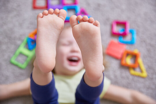 Close-up of the legs of a child laughing on the carpet