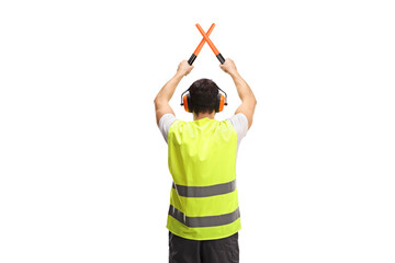 Rear view shot of an marshaller signalling with crossed wands