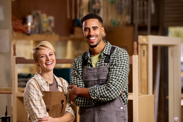 Portrait Of Male And Female Apprentices Working As Carpenters In Furniture Workshop - obrazy, fototapety, plakaty