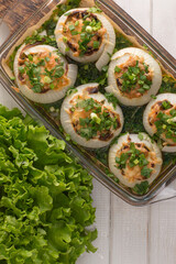 stuffed onions with cheese and vegetables on a wooden board.