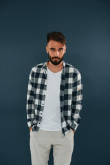 In a checkered shirt. Handsome man is in the studio against blue background