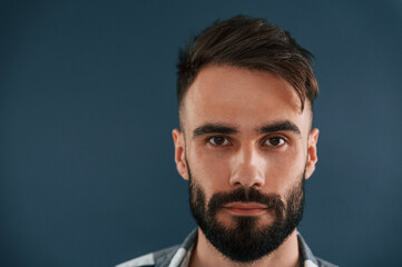 Close up portrait. Handsome man is in the studio against blue background