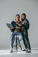 Beautiful man and woman are together in the studio against background. With laptop and tablet in hands