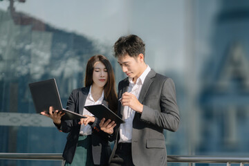 Business team or financial data analysts working with tablets and laptop computers and data graphs together. Plan to analyzing projects outside an office building.