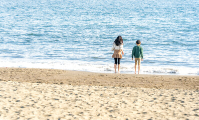 冬の海辺で遊ぶ男の子と女の子