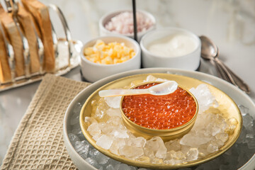 Orange Keta Lachs Kaviar in Dose auf Eis in Glas Schale mit Perlmutt Löffel, gekochte Eier...