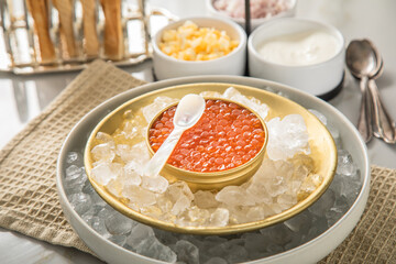 Orange Keta Lachs Kaviar in Dose auf Eis in Glas Schale mit Perlmutt Löffel, gekochte Eier Würfel, Charlotten Zwiebel Würfel, Toast Brot und Saure Sahne auf Serviette und Marmor hell