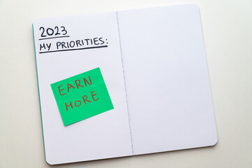 Notebook page with text "2023 Priorities: spend less, earn more". Increase in expenses, inflation, and measures to deal with it.
