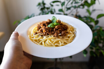 Plate with classic Italian pasta spaghetti bolognese in hand