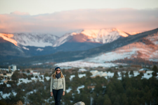 A woman stands against a snowy mountain scene in Truchas, New Mexico.