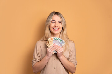 happy caucasian woman with brazil banknotes currency in beige colors. economy, payment, successful...
