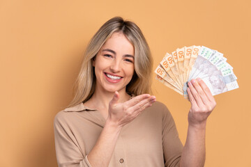 cheerful brazilian woman celebrating successful business money in beige colors. financial, credit,...