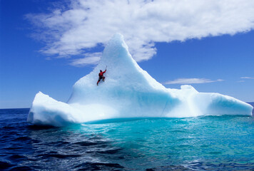Man climbing on iceberg, Labrador, Canada.
