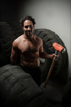 A man with a hammer surrounded by big truck tires during a crossfit class in Mexico City, Mexico.