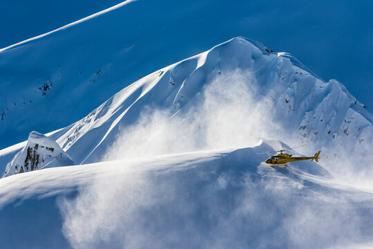 Helicopter taking off from top of snow capped mountain